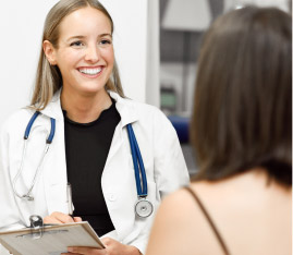 Doctora sonriendo mientras atiende a una paciente para evaluar los síntomas e iniciar una Terapia de Reemplazo Hormonal (TRH).